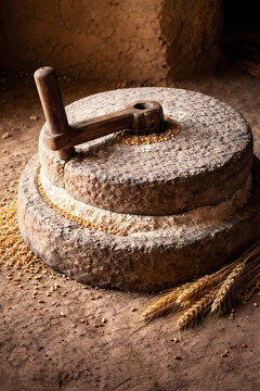 Traditional stone hand mill grinder with wheat grains and flour in a rustic setting