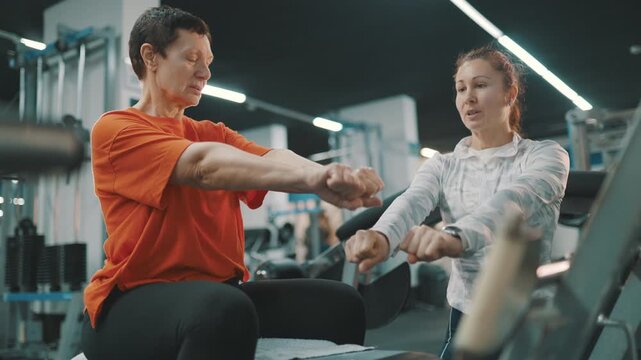 Personal trainer instructing senior woman at the gym