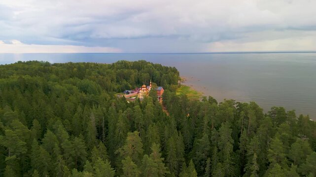 Epic Ladoga lake monastery aerial orbit. 
Cinematic 4K drone panorama of historic 
orthodox Christian skete and isolated 
forest coastline on Konevets island, Russia.
