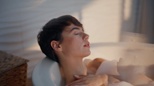 Luxury woman taking bath white foam in home bathroom portrait. Calm girl soaking