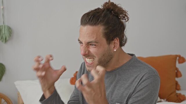 Man on bed shouting with clawing hands and clenched fists in building, motion blur, visible pillow and hanging plant; anger outburst.