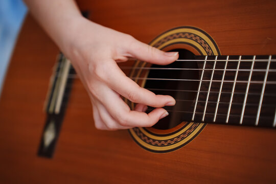 Person playing guitar with right hand while touching strings