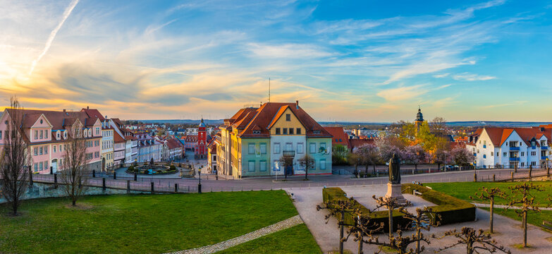 Panoramic view over Gotha with historic city center, market square, monument and colorful houses, wide green foreground and dramatic evening sky showing urban heritage in Thuringia, Germany