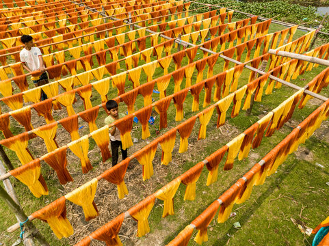 Narayanganj, Bangladesh - 30 March 2026: Aerial view of vibrant, sun-drenched textiles suspended in neat rows, creating a striking pattern of color and texture.