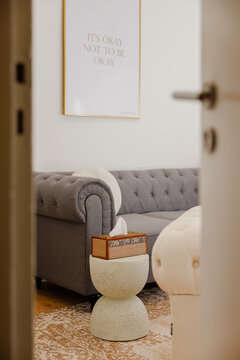 A quiet, intimate view inside a rehabilitation clinic captured from a doorway perspective, showcasing a box of tissues and a motivational poster reading &ldquo;it&rsquo;s ok not to be ok.&rdquo;
