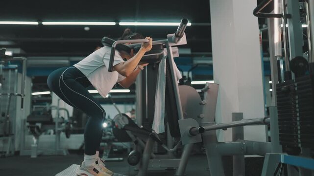 Athletic woman performing hack squats at the gym