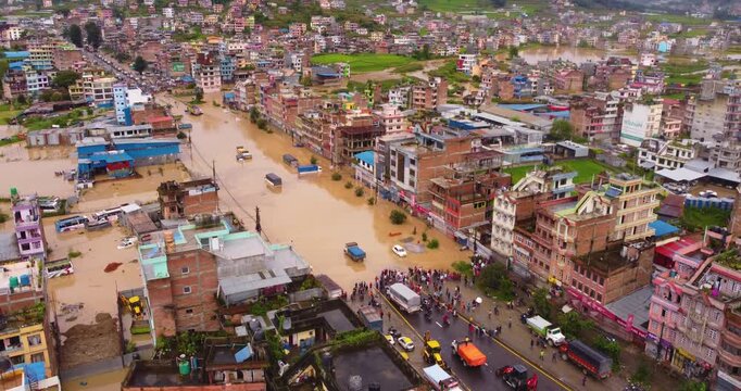 Aerial drone shot showing widespread flooding across Banepa city with residential buildings and agricultural land submerged under water following heavy monsoon rainfall in Nepal.