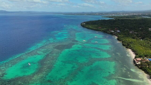 A drone slides right over Panglao Beach reef flats and turquoise water in Panglao, Bohol