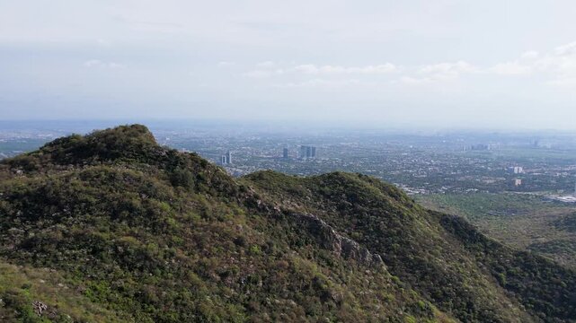 Green Margalla Hills ridge overlooking Islamabad city with distant skyline under hazy sky, Pakistan