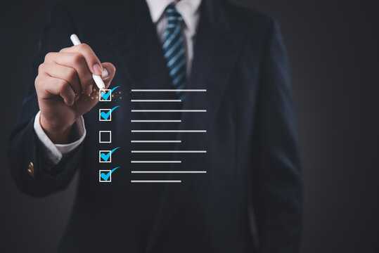 Businessman in suit using stylus pen checking virtual digital checklist. Concept of business quality assurance, project management, workflow automation, compliance audit, and task completion.