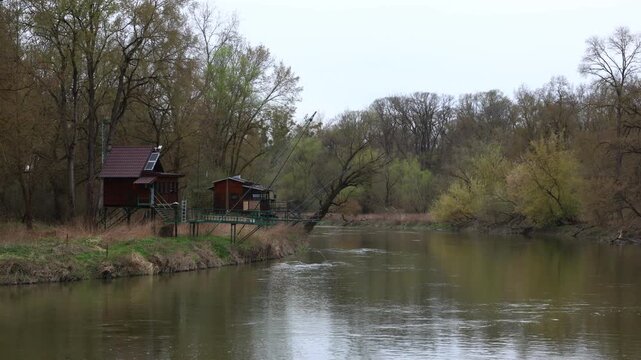 Fishing huts on high stilts along a riverside in floodplain forest, built above rising water levels to withstand seasonal flooding