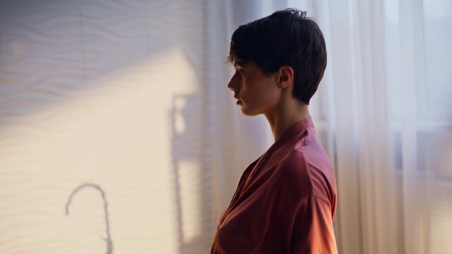 Brunette taking off silk robe standing naked back closeup. Woman spa procedures