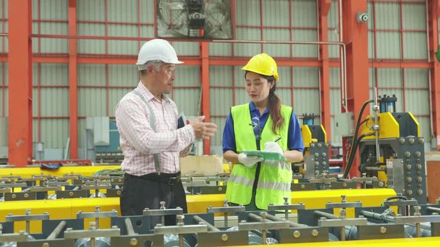 Senior male manager inspected the metal sheet rolling machine together with female workers providing them training and recording the information clipboard inside the metal sheet manufacturing plant.