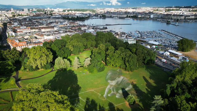 Aerial view of verdant parkland meets the shimmering waters of Lake Geneva, nestled against a backdrop of urban architecture, Geneve, Geneve, Switzerland.