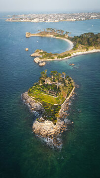 Aerial view of the Pointe de Perharidy casting a serene emerald and sapphire jewel tone across the waters, standing in stately isolation, Roscoff, Finistere, France.
