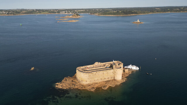 Aerial view of the imposing Chateau du Taureau, bathed in sunlight, standing sentinel in the tranquil bay, a stark contrast to the deep blue sea, Plouezoc'h, Bretagne, France.