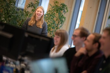 Fototapeta premium Businesswoman presenting to team while colleagues listen in modern office collaborative workspace environment