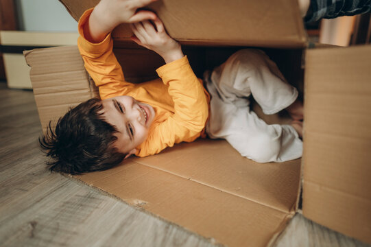 Child having fun playing inside a cardboard box indoors