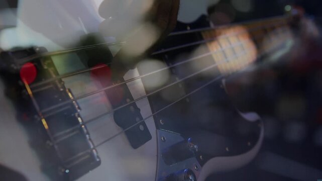Opening close-up showing bassist plucking strings, fretting neck, playing in studio with bokeh