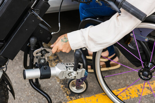 Woman detaching handbike from wheelchair for accessible mobility