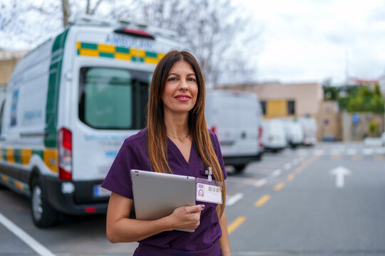Nurse in uniform holding tablet near ambulance outdoors