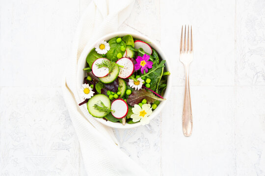 Spring salad with radish cucumber peas edible flowers and dill top view