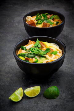 Red Thai curry soup with rice noodles smoked tofu and pak choi in bowls