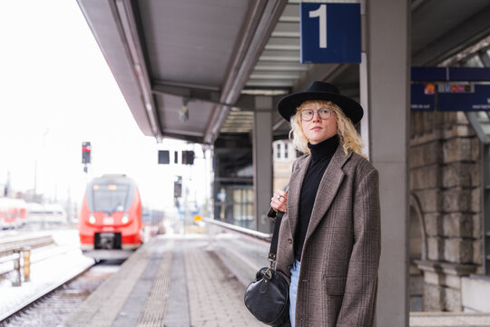 Fashionable commuter waiting at train station platform for public transport
