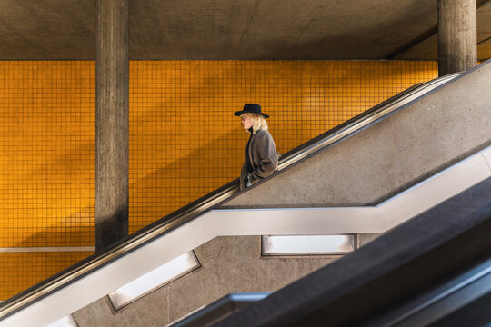 Side view of man with hat commuting on escalator in subway station