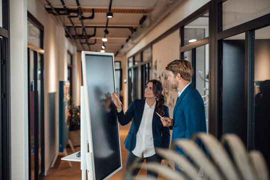 Colleagues discussing project strategy at modern office touchscreen