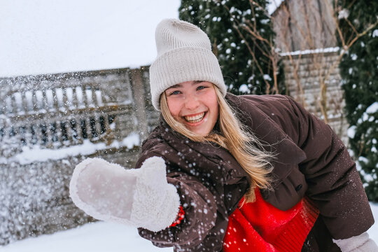 Smiling woman in winter clothing playing snowball fight outdoors
