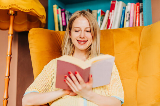 Smiling woman reading a book in a colorful and stylish home interior