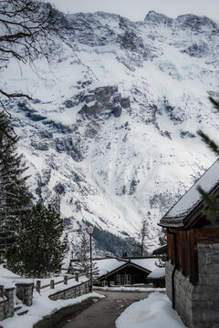 View of snow-laden roofs and winding streets nestled against a majestic backdrop of towering, snow-capped mountains, Murren, Switzerland.