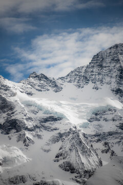 View of snow-capped mountains reaching into the sky, contrasting with the deep blue sky and light clouds, creating a sense of altitude, Murren, Switzerland.