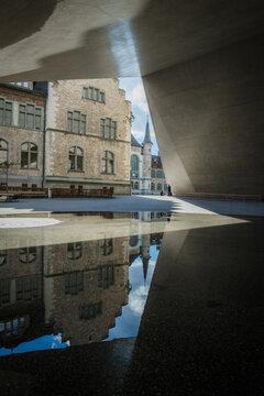 View of the National Museum Zurich reflected in a puddle, a captivating interplay of light and shadow, juxtaposing the old architecture with modern design, Zurich, Switzerland.