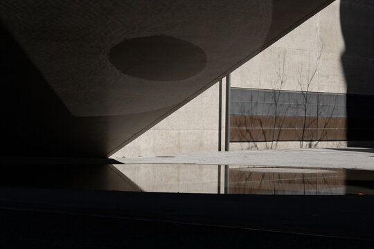 View of stark, geometric shadows dance across textured concrete and still water, reflecting a minimalist, urban landscape in Zurich, Switzerland.