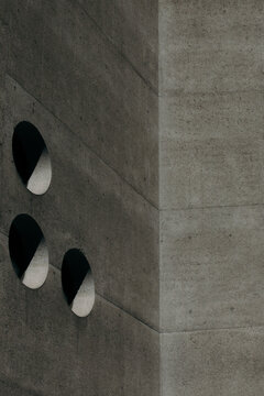 View of stark concrete walls punctuated by circular openings create a modern, minimalist aesthetic, emphasizing texture and shadow, Zurich, Switzerland.
