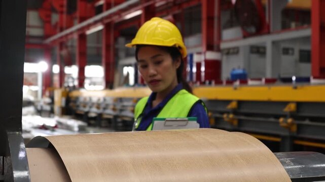 Female worker inspect rust proof coated corrugated metal sheets ensuring strength aesthetics before shipment distributors within the industrial metal sheet manufacturing plant.
