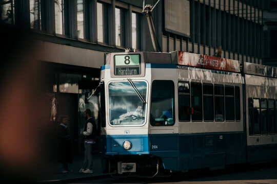 Zurich, Switzerland - 02 April 2023: View of a blue and white tram at the Hardturm stop reflects the city's sleek modernity against the backdrop of the National Museum Zurich.