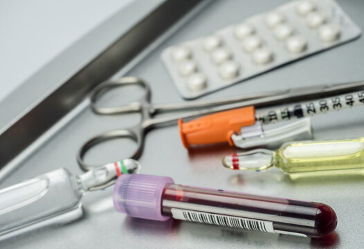Syringes and scissors of suture in a tray metal, conceptual image