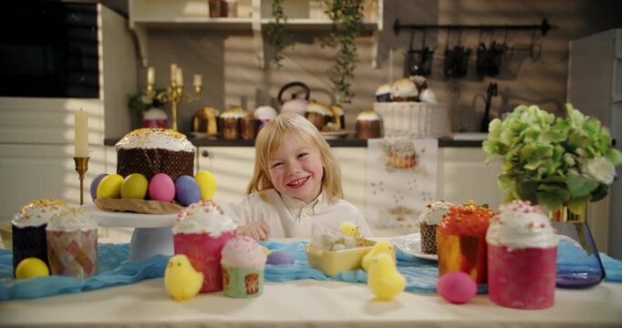 Little boy hiding behind Easter table and smiling
