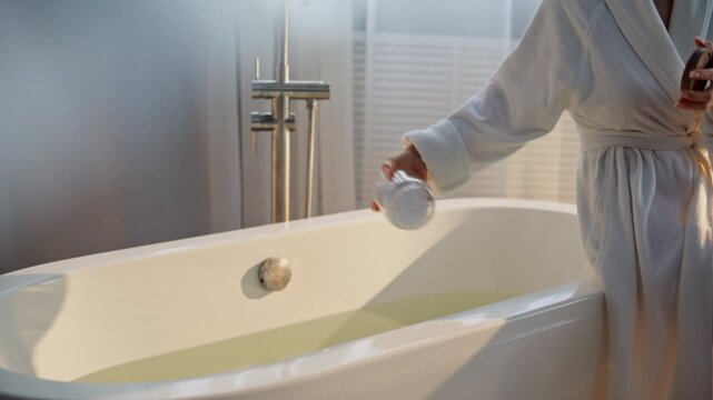 Bathrobe lady salting bathtub water morning room. Closeup woman pouring sea salt