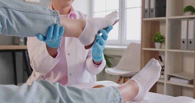 Close-up of female professional orthopedist fits custom orthopedic insole to woman patient foot during clinical examination. Therapy, rehabilitation, medical consultation, flat feet correction