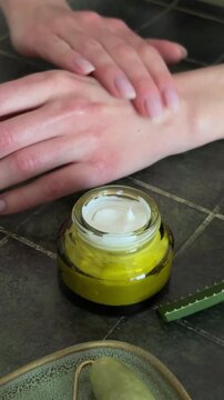 Macro shot of a finger touching white moisturizing cream in a glass jar, skincare concept