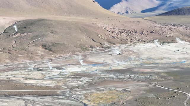 Cinematic flying forward over the steaming geothermal vents of El Tatio at dawn, revealing the rugged volcanic landscape of the Chilean Altiplano