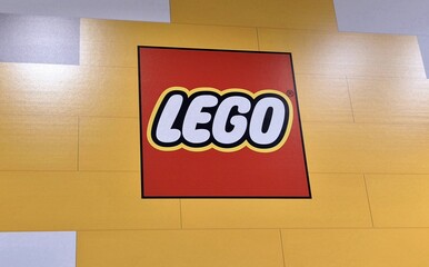 Naklejka premium The image shows the iconic red, white, and yellow LEGO logo centered on a yellow-brick patterned wall taken on April 10, 2026 in Bucharest, Romania.