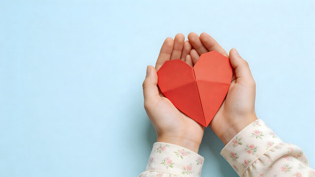 Hands holding red origami heart