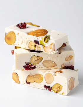 Rectangular white nougat candy bars with almonds, pistachios and dried cranberries. Delicious snack, appetizing sweet food, tasty treat.