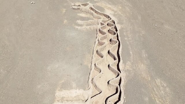 Cinematic pulling back to reveal the full "Two-Headed Llama" (La Llama de Dos Cabezas) geoglyph in the arid landscape of Vallecito, near San Pedro de Atacama