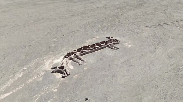 Cinematic orbit circling the "Two-Headed Llama" (La Llama de Dos Cabezas) geoglyph in the Vallecito area near San Pedro de Atacama, Chile